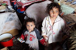 Two children, one holding a toy, smiling.