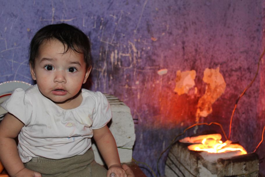 A baby sitting in front of a fire pit.