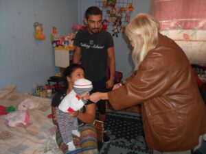 A woman handing something to a child in her arms.