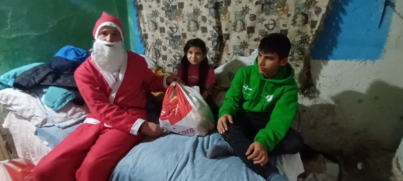A man dressed as santa claus sitting next to two children.