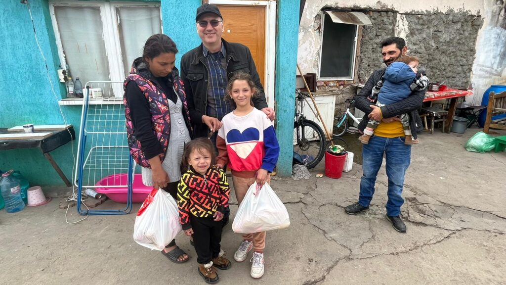 A family standing in front of a building with bags.