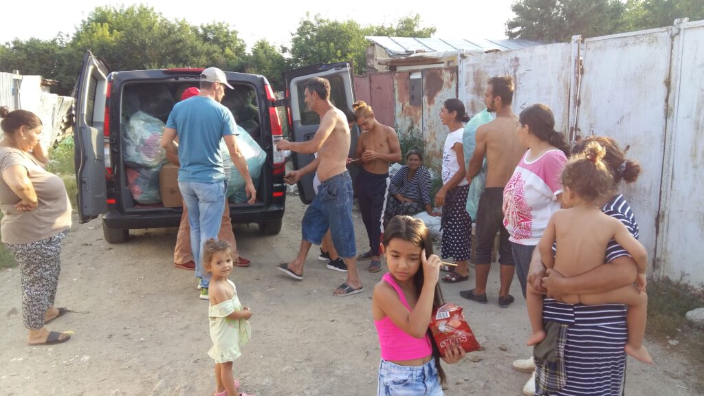 A group of people standing around in front of some cars.