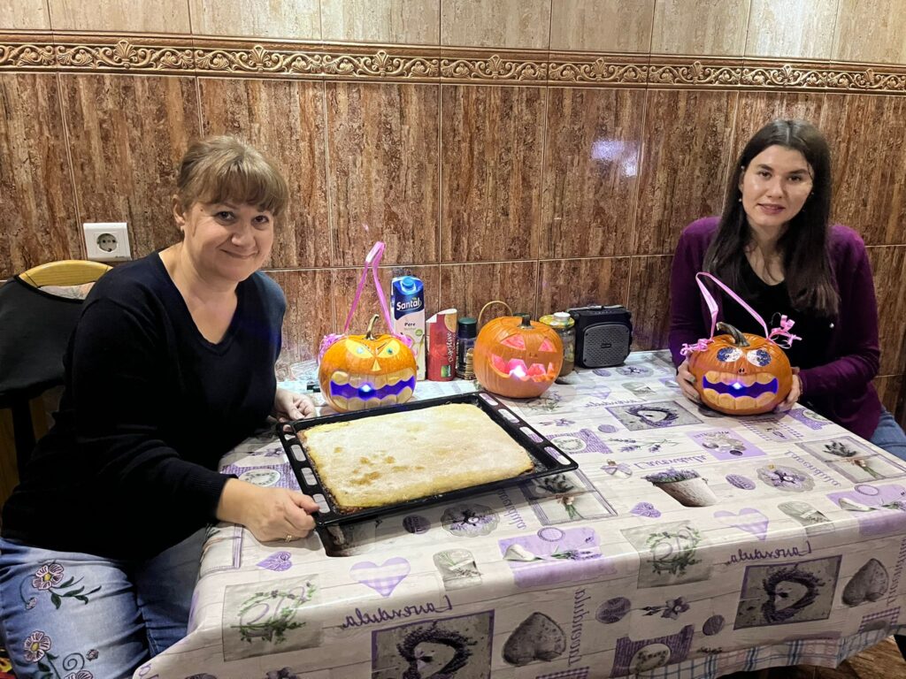 Two women sitting at a table with some cake on it
