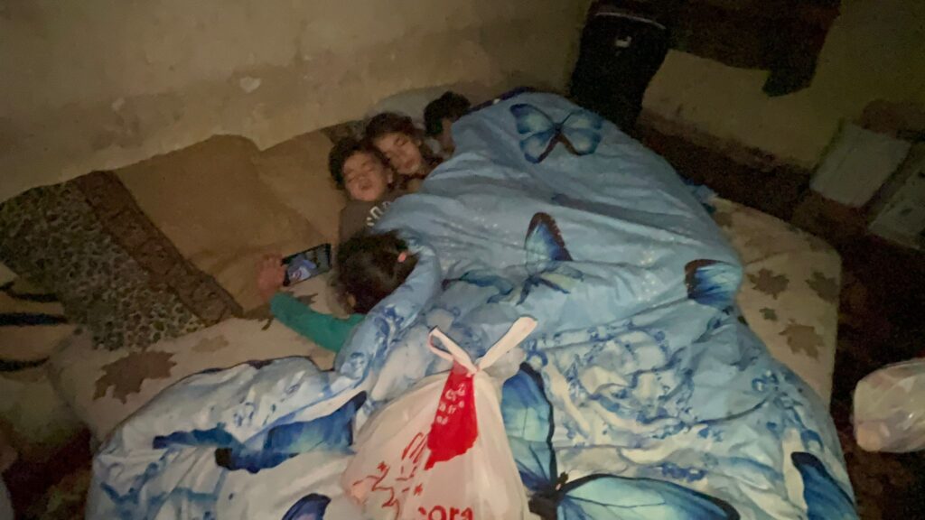 Two children laying on a bed with their bags