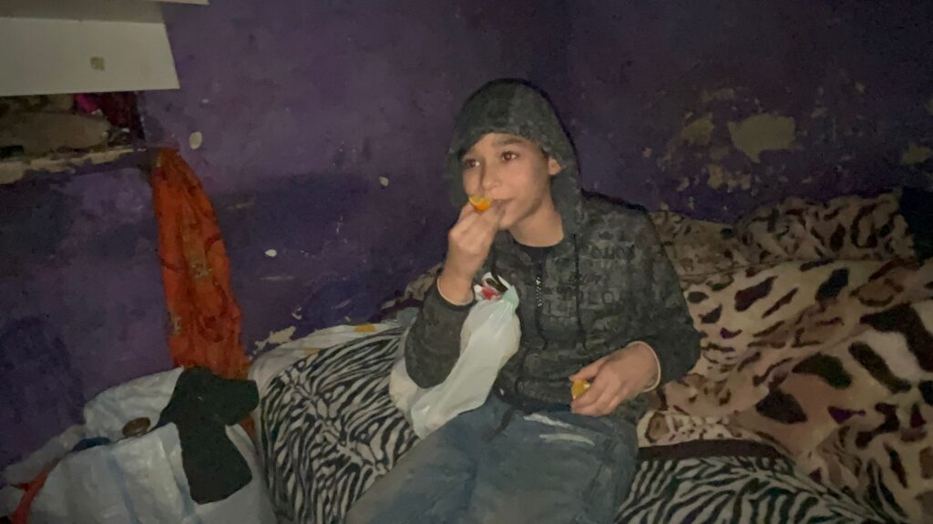 A young man sitting on top of a couch eating food.