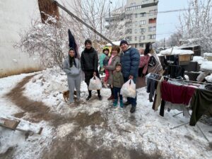 Family with grocery bags in snowy courtyard
