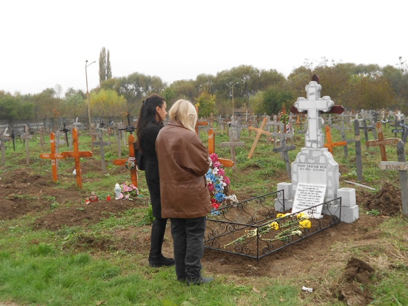 Two women standing in front of a grave.