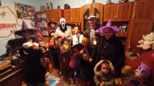 Costumed adults and children holding Halloween bags
