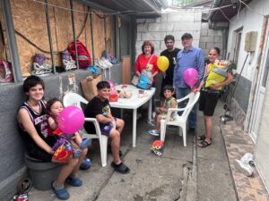 Group celebrates with balloons around backyard table